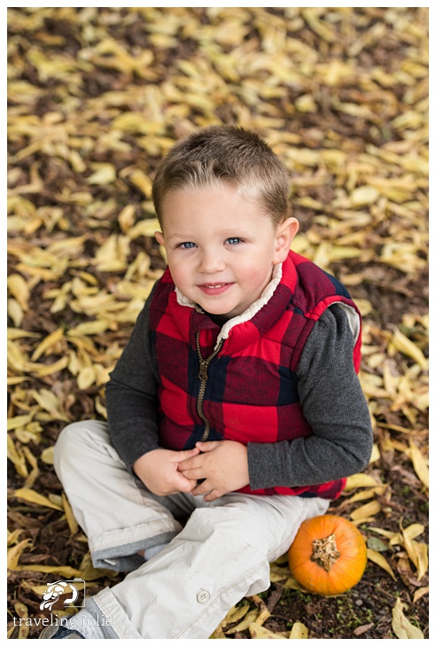 little boy in fall leaves with pumpkin